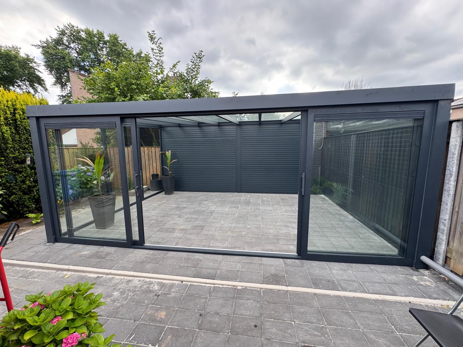Zwarte aluminium tuinkamer in een groene tuin